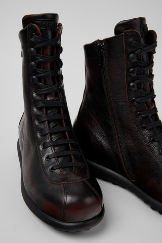 Close-up angled view of Camper Pelotas burgundy leather mid boots showing calfskin texture and signature rubber outsole