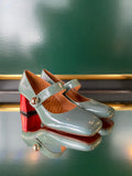 Pair of high-heeled shoes with straps on a green background