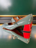Pair of high-heeled shoes with red accents on a green surface