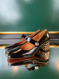 Chie Mihara VYKAR Black heels in glossy black leather shown at an angle with a Mary Jane strap, gold button and graphic patterned heel