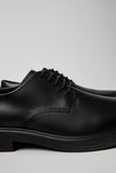 Close-up of Dean black leather men’s shoes showing texture and stitching on a white background