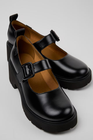 Pair of black platform shoes with buckles on a light gray background