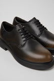 Angled close-up of Dean brown and black calfskin leather shoes showing texture and outsole detail