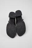Black shoes with embossed sole design on a light gray background