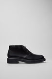 Side view of Dean black leather men’s ankle boots on a white background