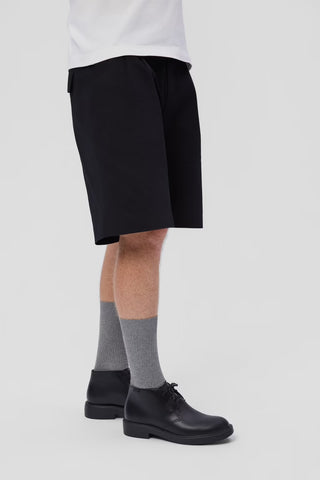 Gentleman wearing black shorts, gray socks, and black shoes on a light gray background