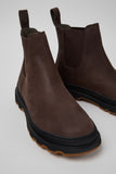 Angled close-up of brown nubuck ankle boots highlighting leather texture and outsole details on a white background.