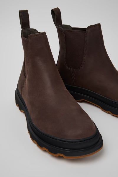 Angled close-up of brown nubuck ankle boots highlighting leather texture and outsole details on a white background.