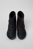 Pair of black winter boots with green accents on a light gray background