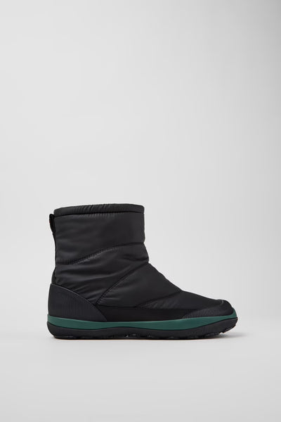 Black winter boot with green trim on a light gray background