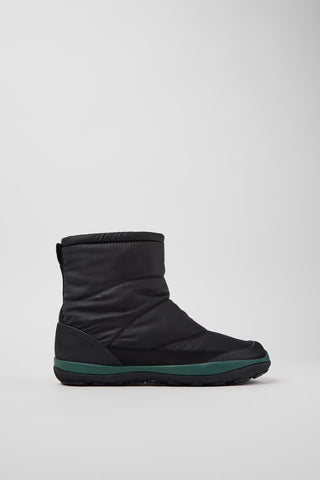 Black winter boot with green trim on a light gray background