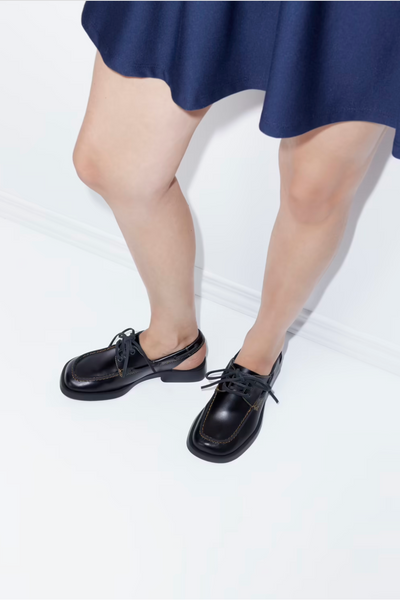 Donna black open-back leather shoes styled with a blue skirt