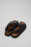 Rear angled view of black Lluc Sandal showing leather straps and cushioned brown footbed.
