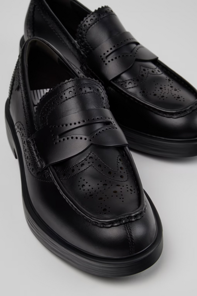 Close-up of black Camper Twins leather moccasins with brogue perforations, penny-loafer strap and rounded toe.