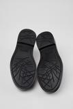 Bottom view of black Camper Twins moccasins showing the black XL EXTRALIGHT® EVA outsoles with textured tread.