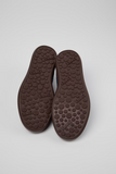 Bottom view of Camper Pelotas Soller sneakers showing the brown rubber outsoles with raised circular tread.
