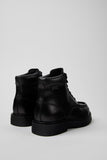 Rear three-quarter view of Camper Alaro black leather ankle boots showing the heel, ankle shaft and rubber sole