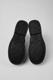 Underside of Camper Alaro black leather ankle boots showing the rubber outsole and tread pattern