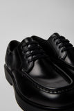Close-up of Camper Alaro black leather shoes showing the smooth leather upper, stitching and sole details