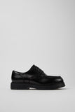 Side view of Camper Alaro men's black leather shoes showing the clean silhouette and substantial rubber sole