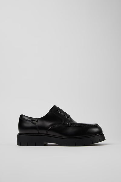 Side view of Camper Alaro men's black leather shoes showing the clean silhouette and substantial rubber sole