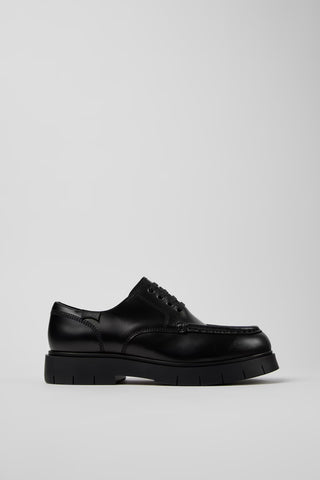 Side view of Camper Alaro men's black leather shoes showing the clean silhouette and substantial rubber sole
