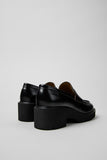 Rear three-quarter view of Camper Milah black leather moccasins showing the heel and sole profile