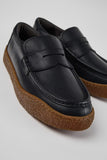 Close-up of Camper Peu Terreno black leather moccasins showing the leather upper, stitching and rubber sole