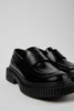 Close-up of Camper Pix Berlin black leather loafers showing the broad leather strap and squared toe