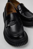 Close-up of Camper Pix London black leather heeled loafers showing the smooth leather and penny-loafer detailing