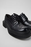 Close-up of Camper Twins black leather shoes showing the contrasting details of the TWINS design